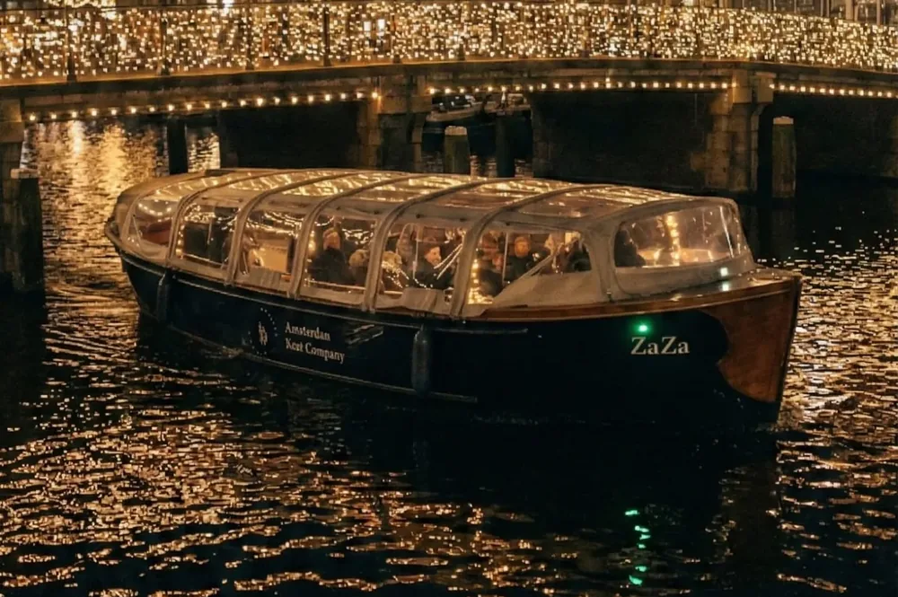 De Zaza met gesloten kap vaart onder een verlichte brug door tijdens het Amsterdam Light Festival